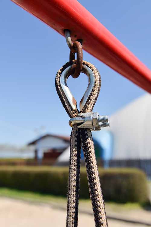 A close up of a metal swing attachment on a soft focus background.