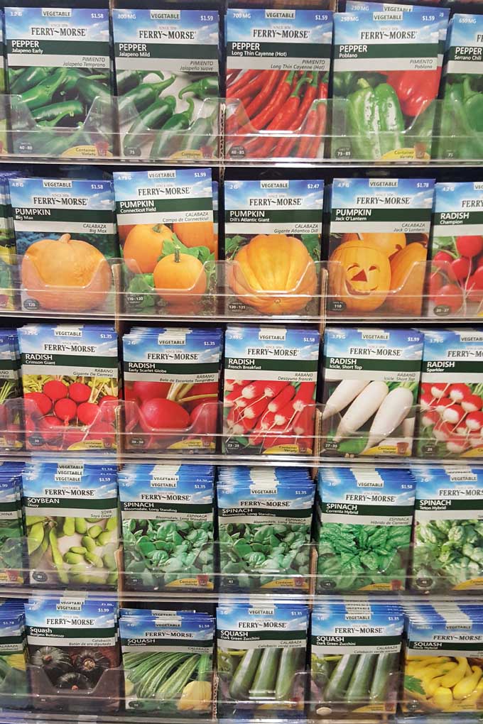A close up vertical image of a rack of seed packets in a garden center.