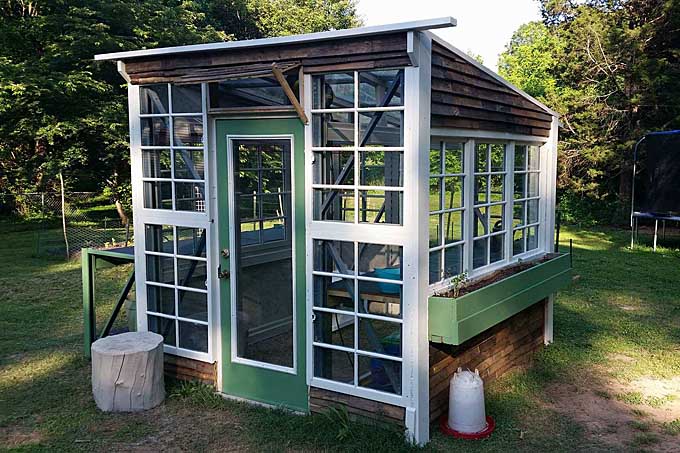 A close up of a DIY greenhouse made out of recycled materials.