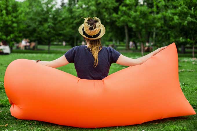 The back of an orange inflatable couch with a you women sitting on it.