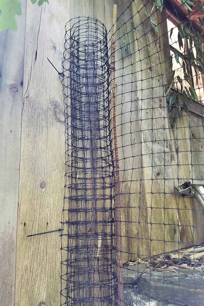 A partial roll of netting attached to a wooden structure, with the remainder of the roll stretched to the right to create a barrier fence.