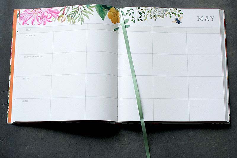 A close up picture of the internal pages of the Royal Horticultural Society "A Gardener's Five Year Record Book" showing gridlines and colorful illustrations on the top of the frame.