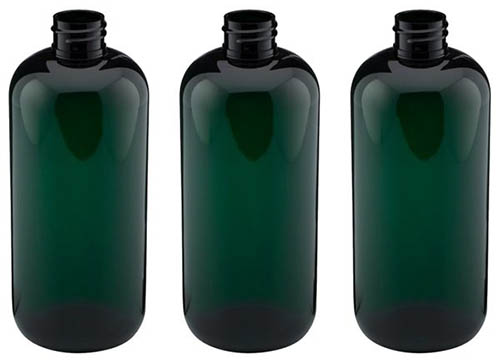 A close up of a set of three dark green bottles on a white background.