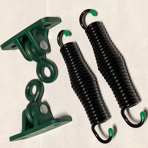 A close up of two black metal springs and two green metal hanging brackets set on a white surface.