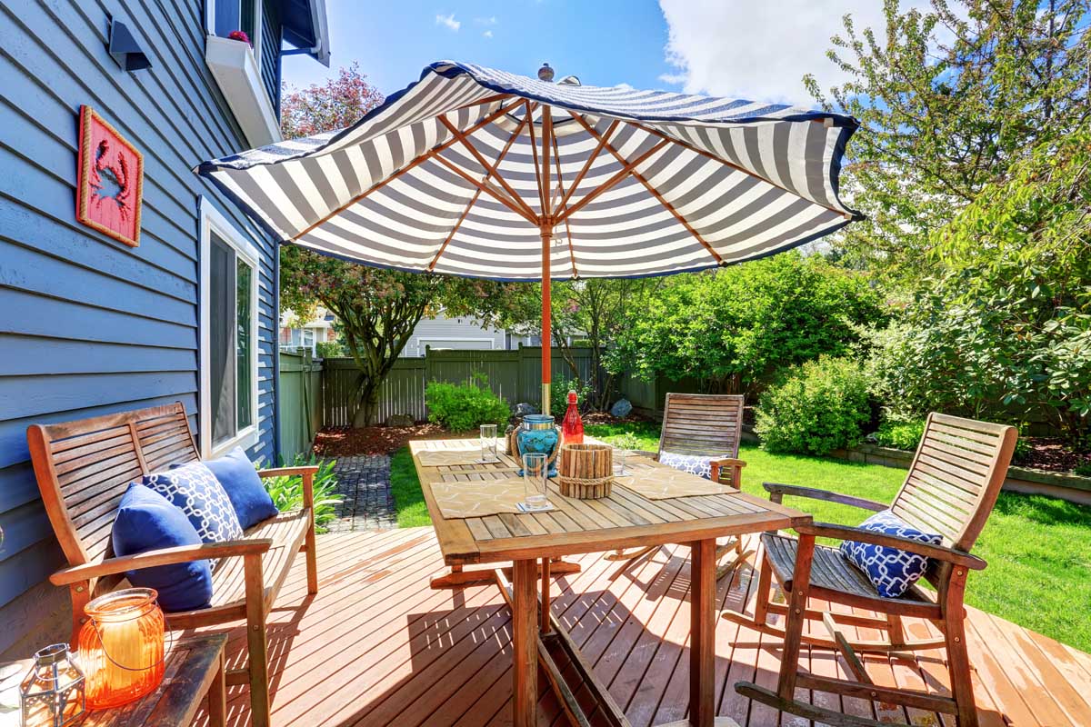 A striped market style umbrella on the back deck of a typical suburban home.