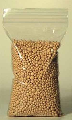 A close up vertical image of a small bag of bonsai fertilizer pellets.