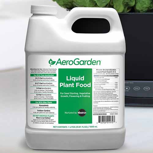 A close up square image of the packaging of MiracleGro Liquid Plant Food set on a gray surface.