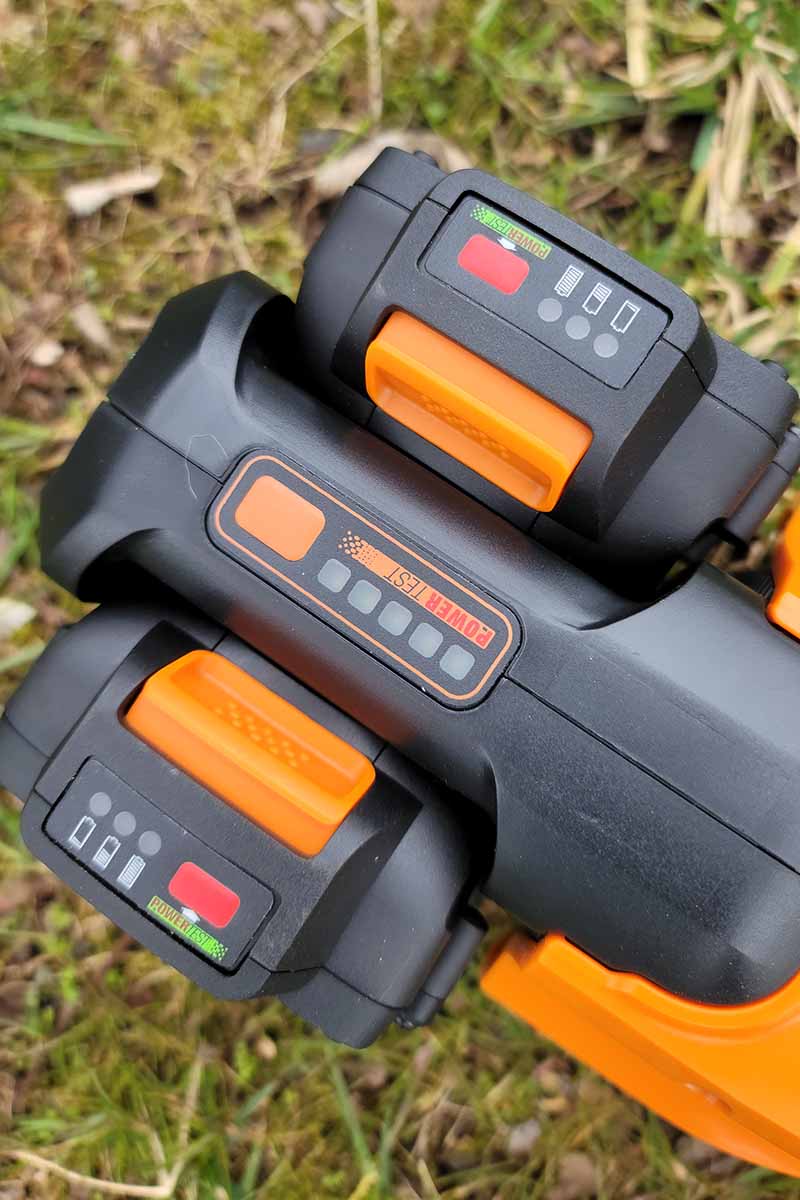 A close up vertical image of a weed eater with batteries installed.