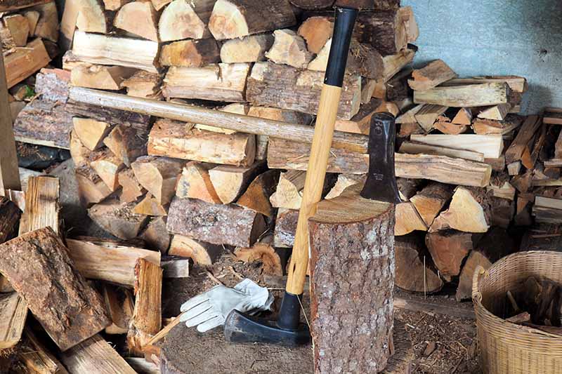 A close up horizontal image of two large splitting mauls in a woodshed.