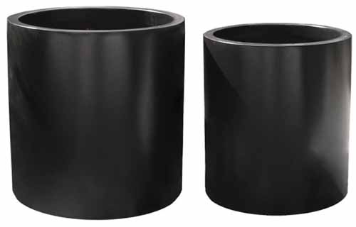 A close up horizontal image of two black fiberglass planters isolated on a white background.
