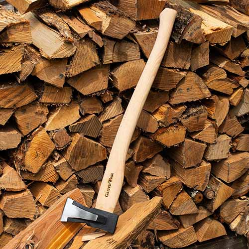 A close up square image of a Garrett Wade Mid-Weight Splitting Maul set on a wood pile.