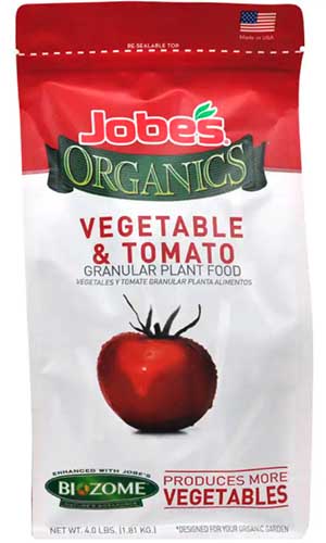 A close up vertical image of the packaging of Jobe's Vegetable and Tomato granular plant food isolated on a white background.