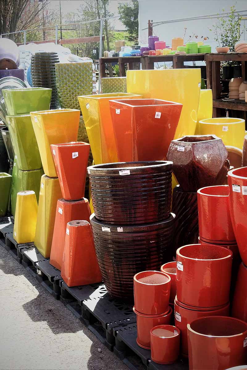 A close up vertical image of a variety of different decorative pots and containers for sale at a garden center.