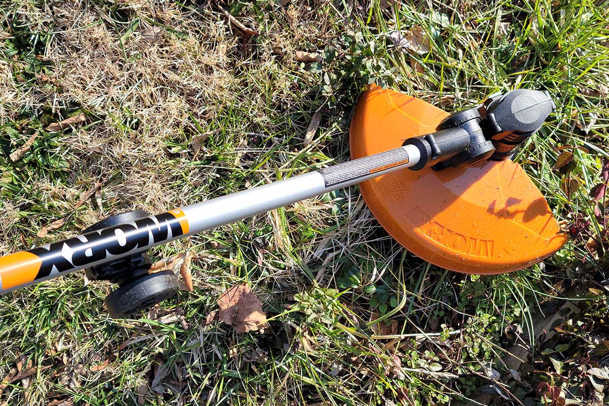 A close up horizontal image of the Worx WG-184 Lawn Trimmer and Edger working on a large section of weeds on a sunny day.