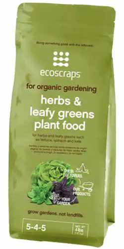 A close up of a bag of Ecoscraps Herbs and Leafy Greens Plant Food isolated on a white background.