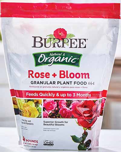 A close up of the packaging of Burpee Rose and Bloom Granular Plant Food.