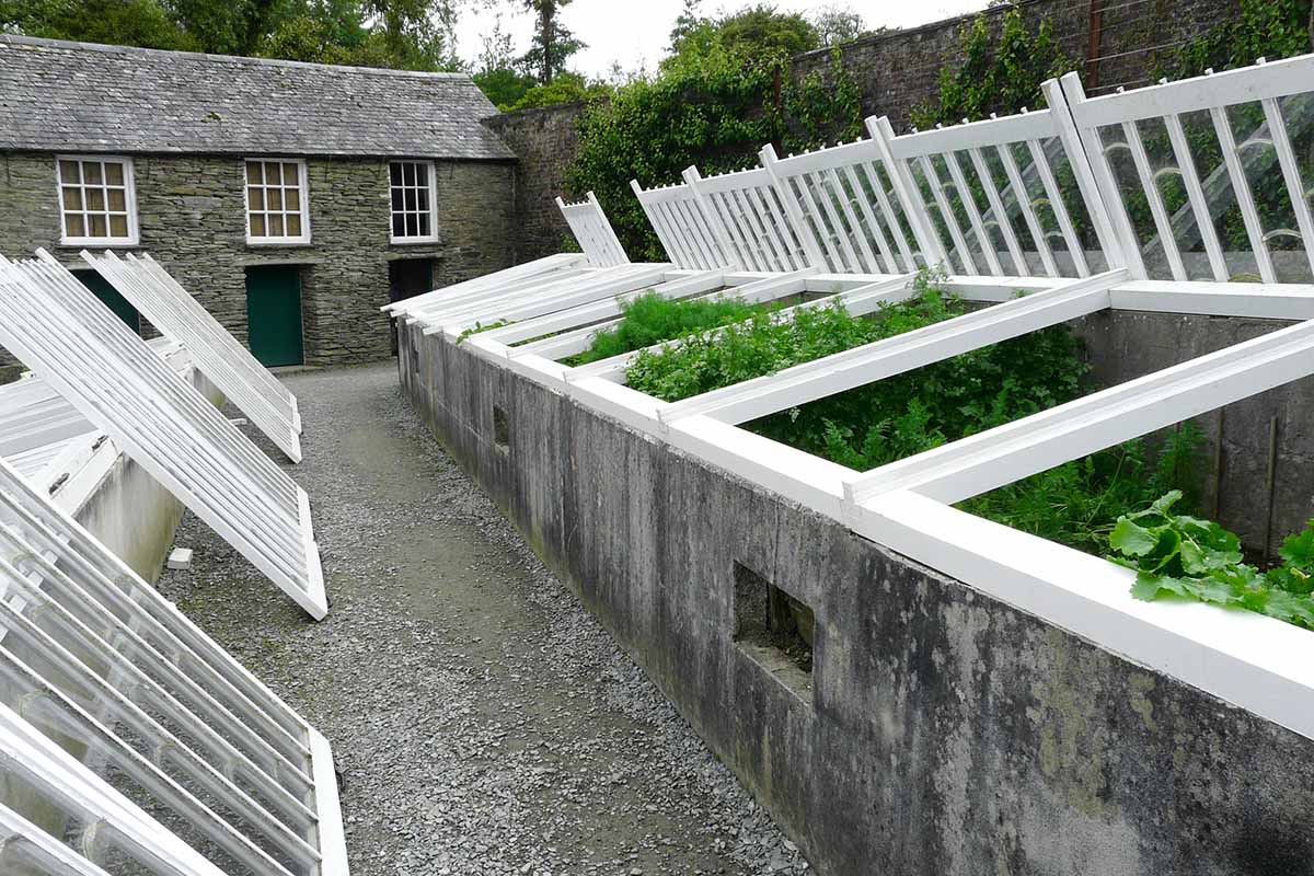 A horizontal image of concrete cold frames outside a stone cottage on a gloomy British autumn day.