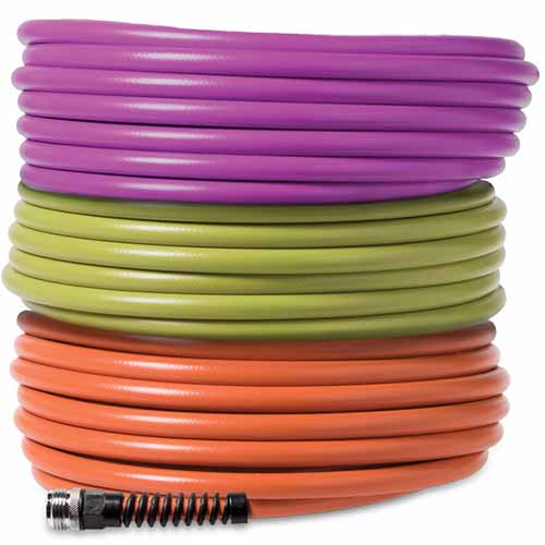 A close up of three hose reels in purple, green, and orange stacked on top of each other isolated on a white background.