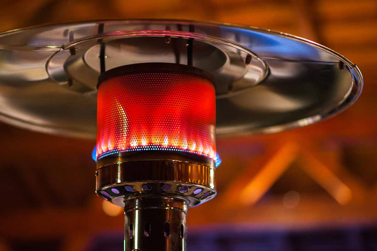 A close up horizontal image of a gas fired patio heater pictured on a soft focus background.