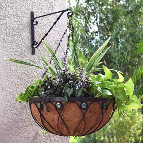 A square image of a decorative metal basket lined with coconut fiber, suspended from a wall with a bracket.