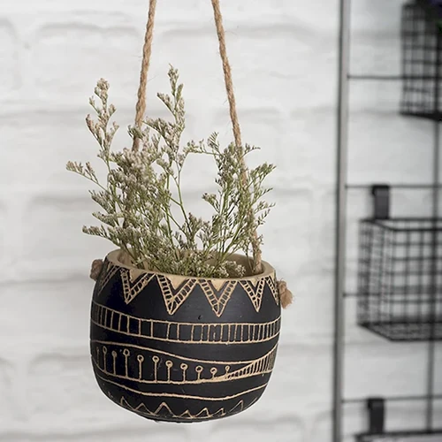 A close up square image of cement hanging planter on a patio.