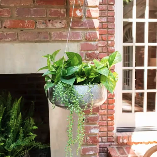 A square image of a silver metal hanging planter in a residence.