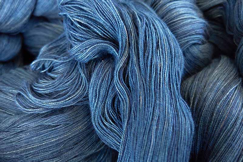 A close up horizontal image of blue wool dyed with indigo.