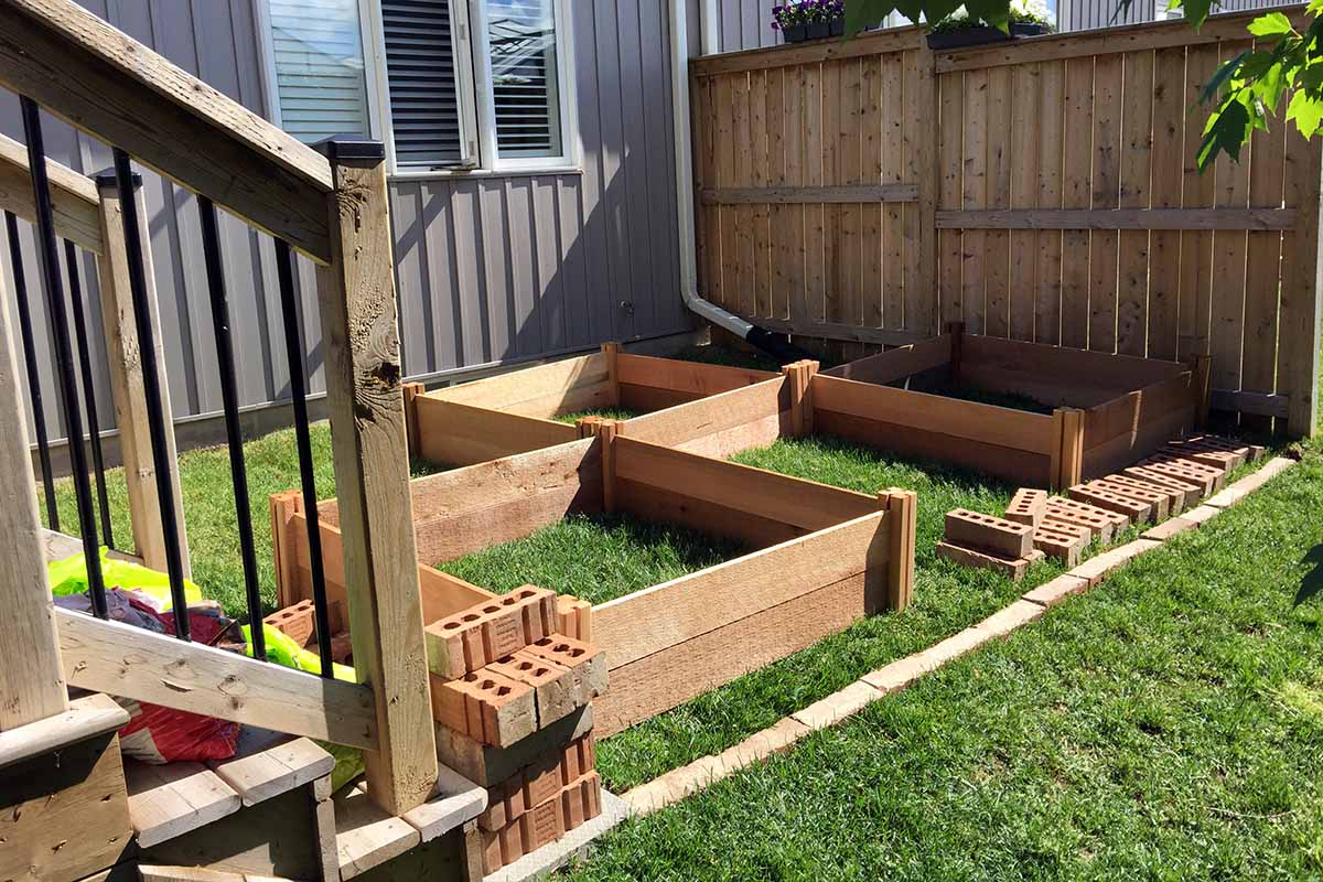 A horizontal image of wooden planters being constructed in a small backyard.