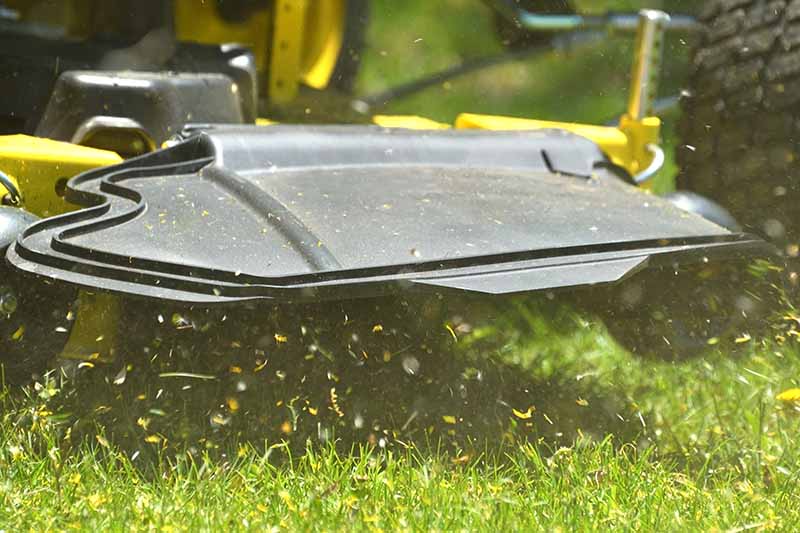 A close up horizontal image of the mowing deck of a lawn mower using side discharge.