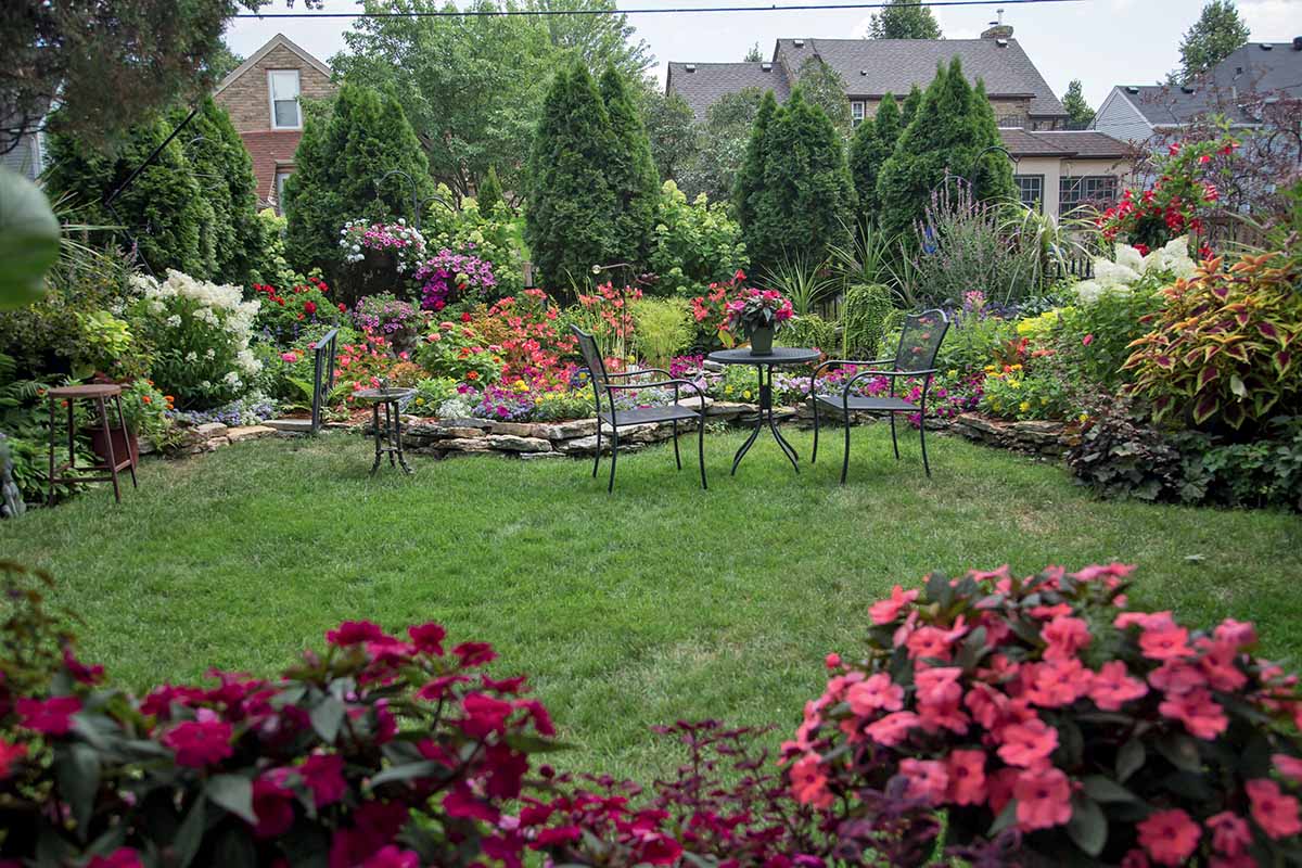 A horizontal image of a garden seating area surrounded by colorful borders.
