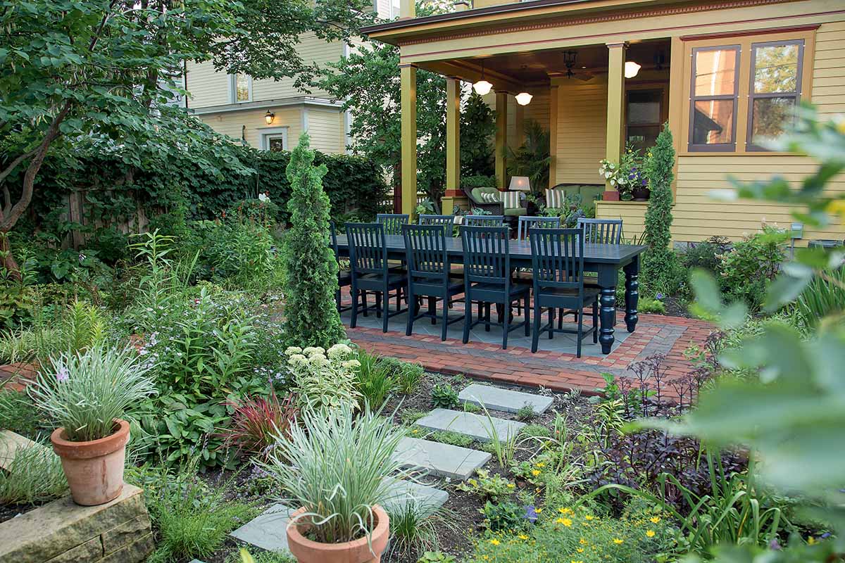 A horizontal image of a formal outdoor dining area surrounded by neat perennial plantings.