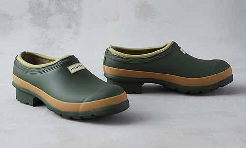 A close up of two Hunter women's garden clog in vintage green set on a gray surface.