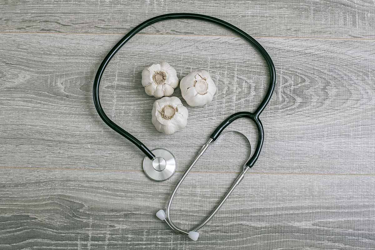 A close up horizontal image of a stethoscope on a light gray wooden surface.