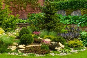 A horizontal image of a formal garden with rockeries and borders growing a variety of different plants.