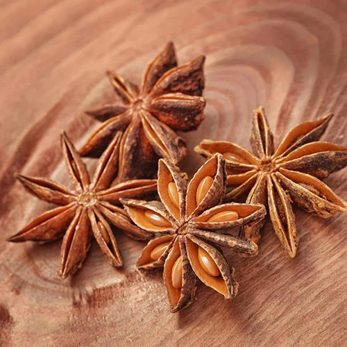 A close up of star anise seeds set on a wooden surface.