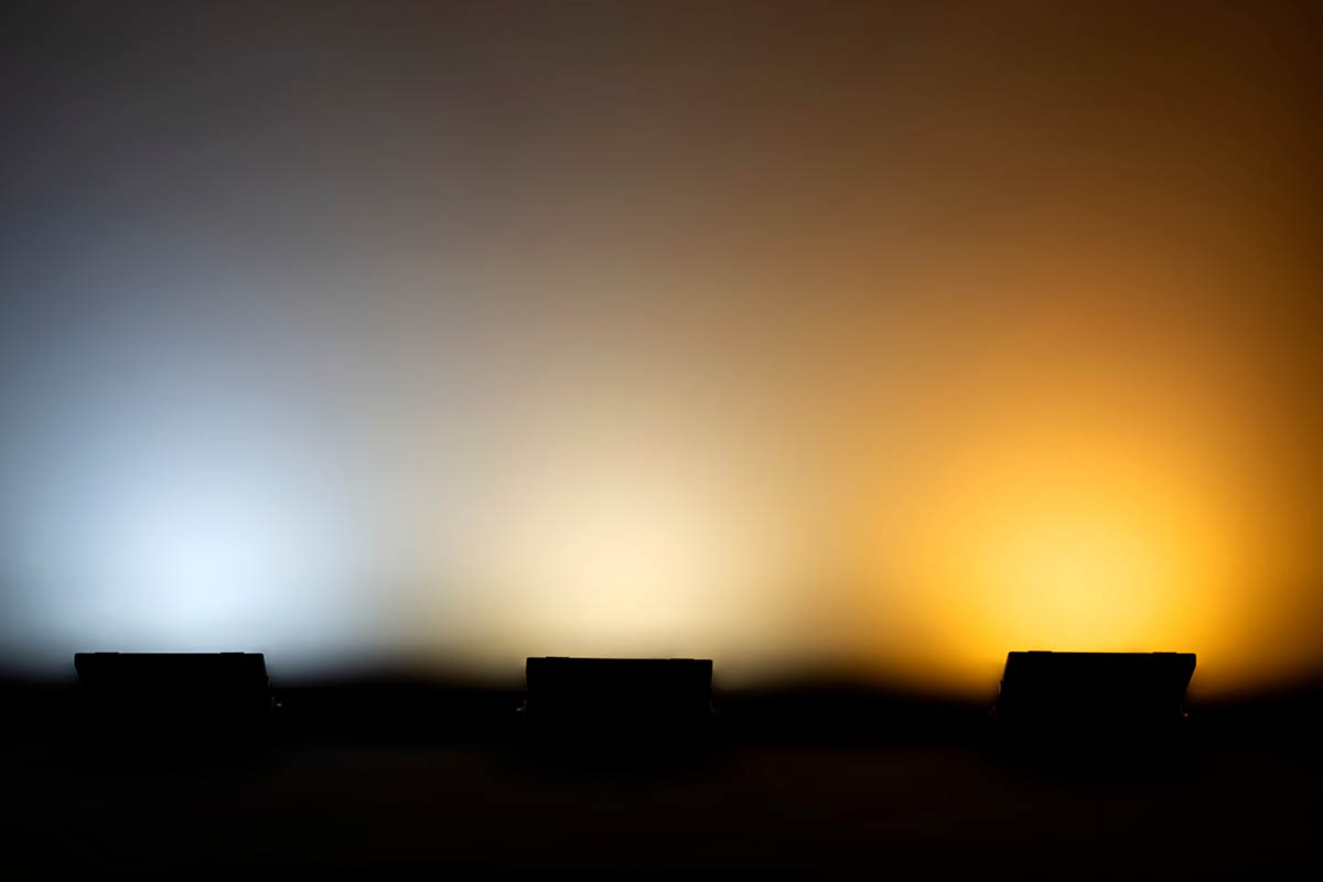 A horizontal image of three different lights illuminating a wall so show the difference between color temperatures.