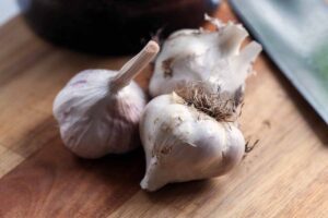 A close up horizontal image of three 'Polish Hardneck' garlic cloves set on a wooden surface.