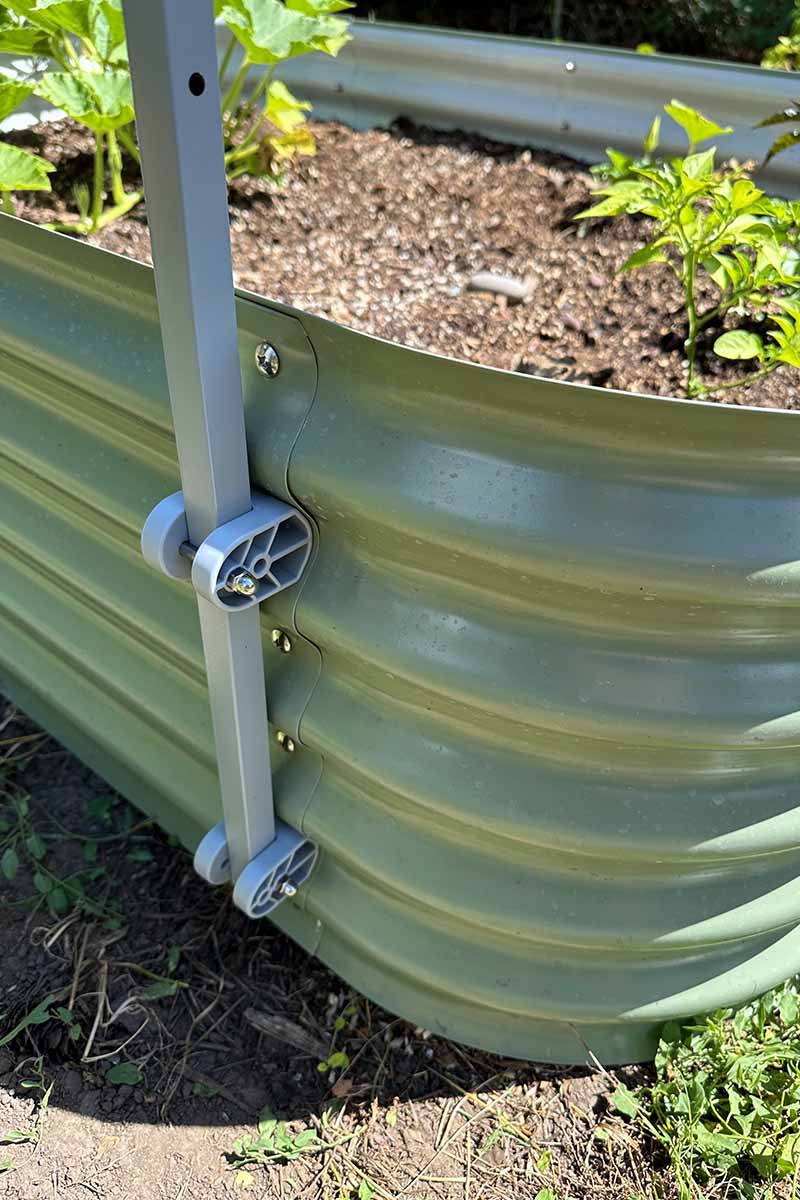 A close up vertical image of the outside of a light green Vego Garden metal raised garden with a trellis attached.
