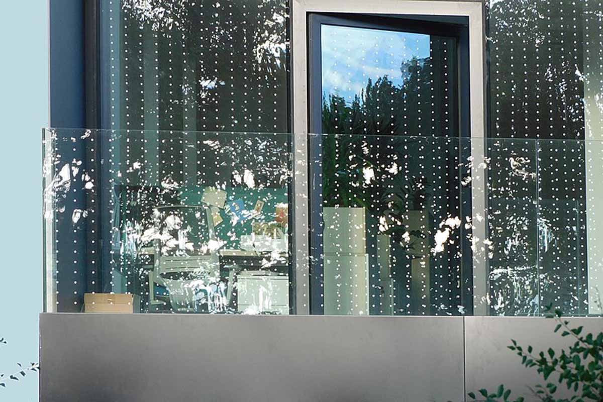 A horizontal shot of a large picture window and sliding glass door with dotted glass deterrents.