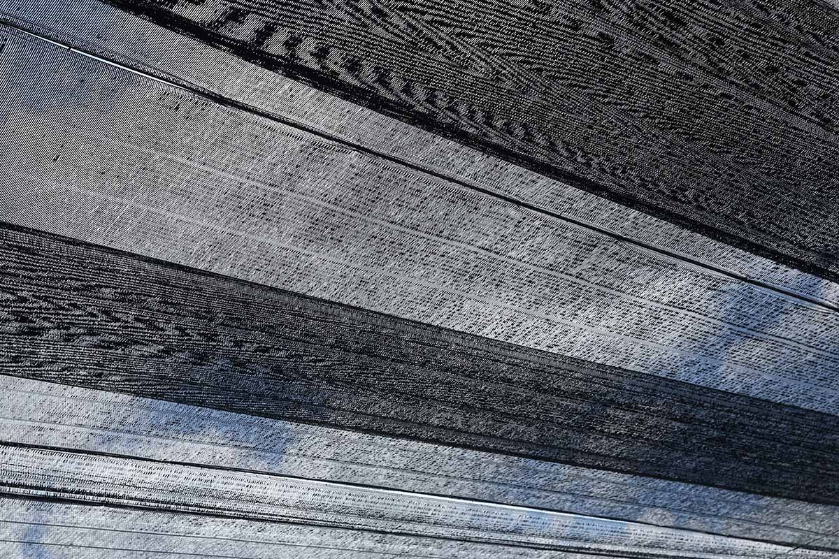 A horizontal shot of a shade cloth stretched across the top of a greenhouse.