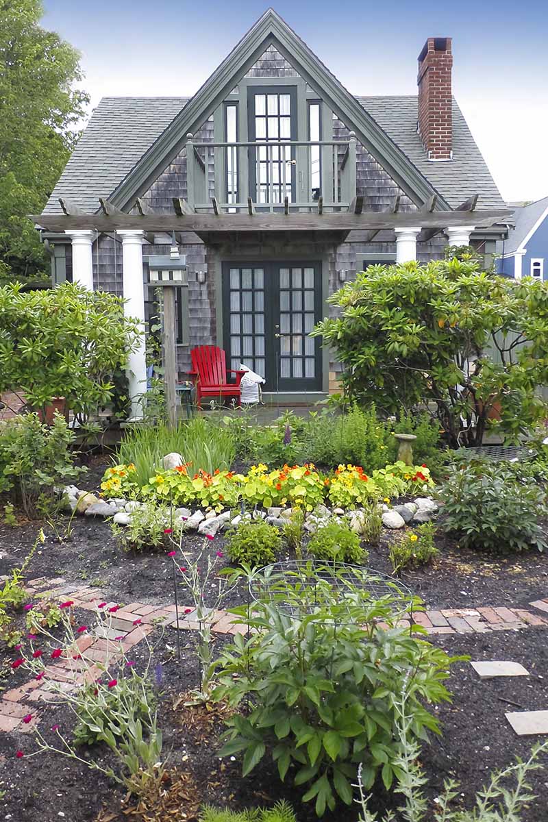 A close up vertical image of a lovely residence with a beautiful elegant cottage garden.
