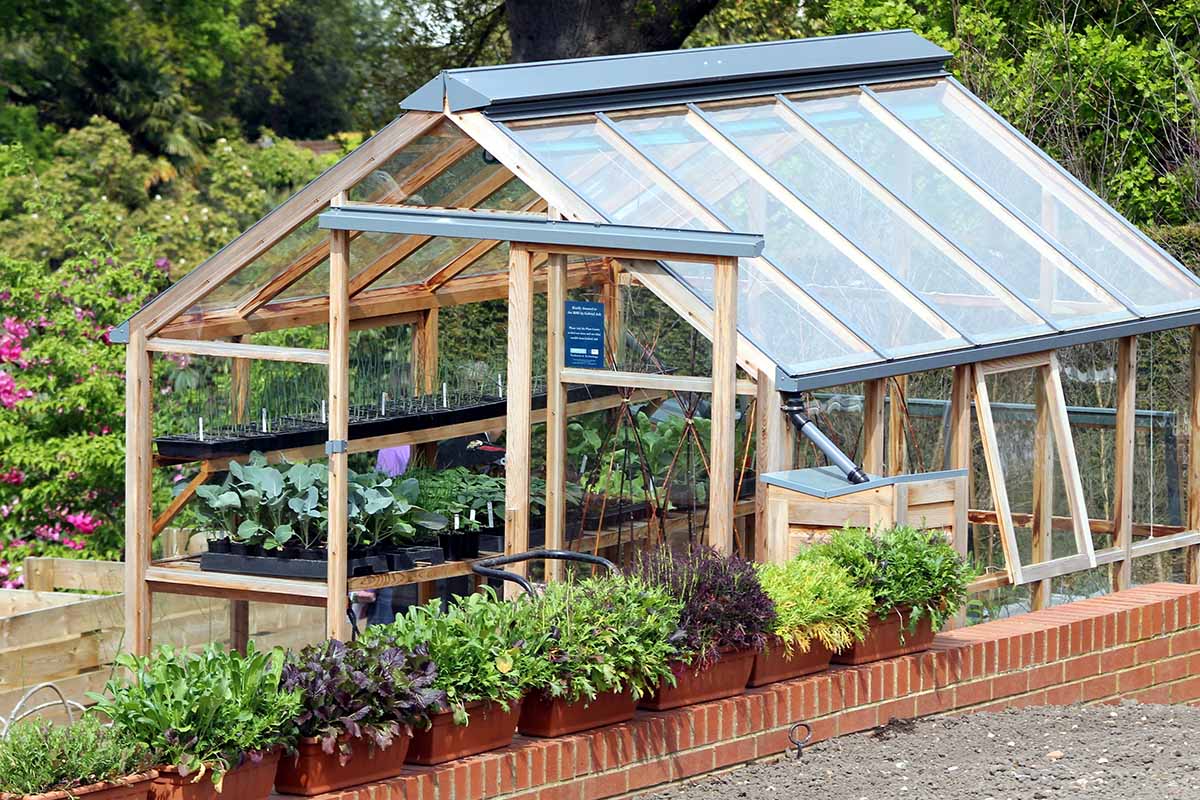 A close up horizontal image of a greenhouse in a formal garden.