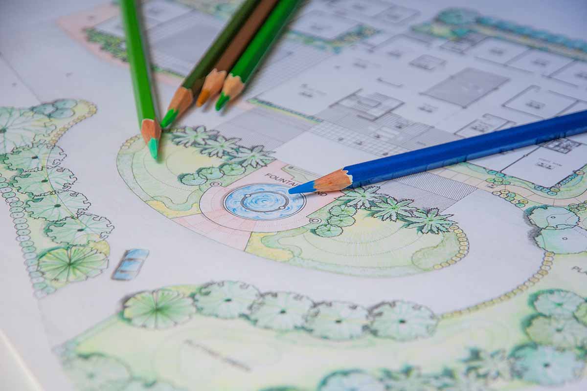 A close up horizontal image of a plan of a landscape layout drawn on a piece of paper with colored pencils.