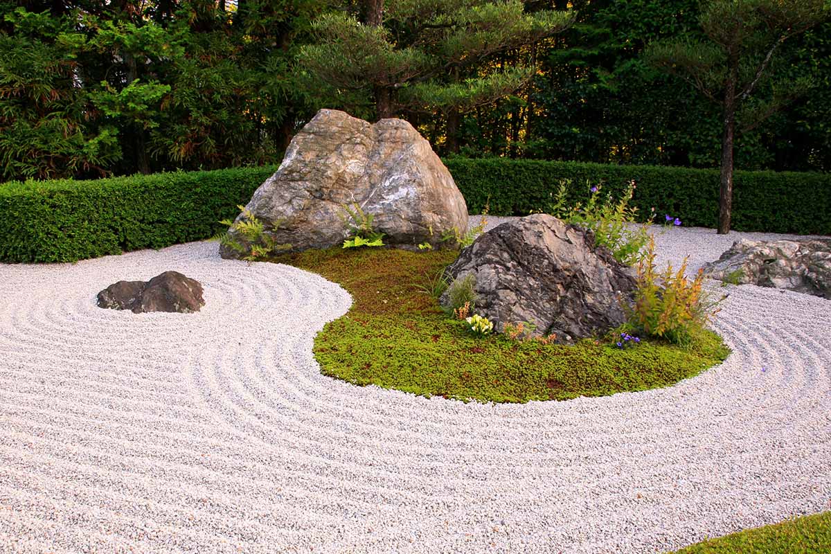 A horizontal shot of a stone garden (karesansui) containing several angular rocks and smaller stones resembling the cliffs of the island of Horai, with a streamock. The garden is located in at the Taizo-in temple in Kyoto, Japan.