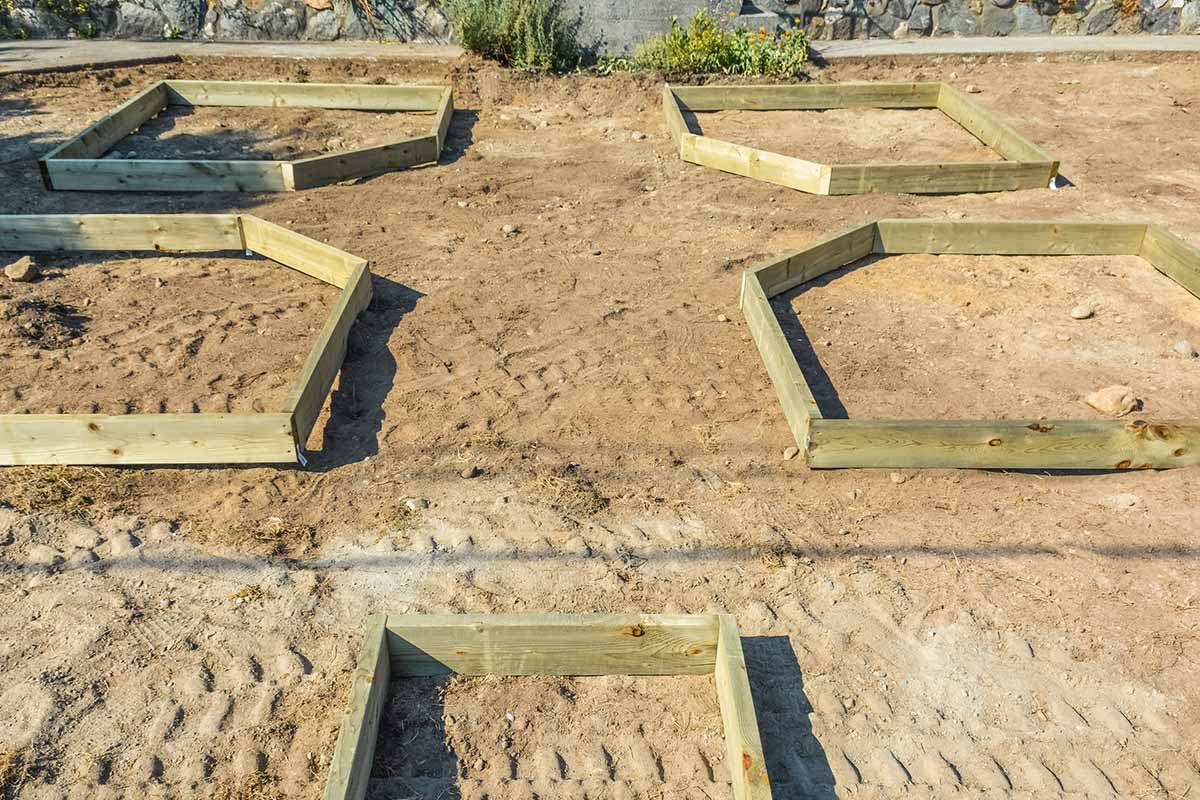 A horizontal image of wooden raised garden beds set out in a cleared backyard.