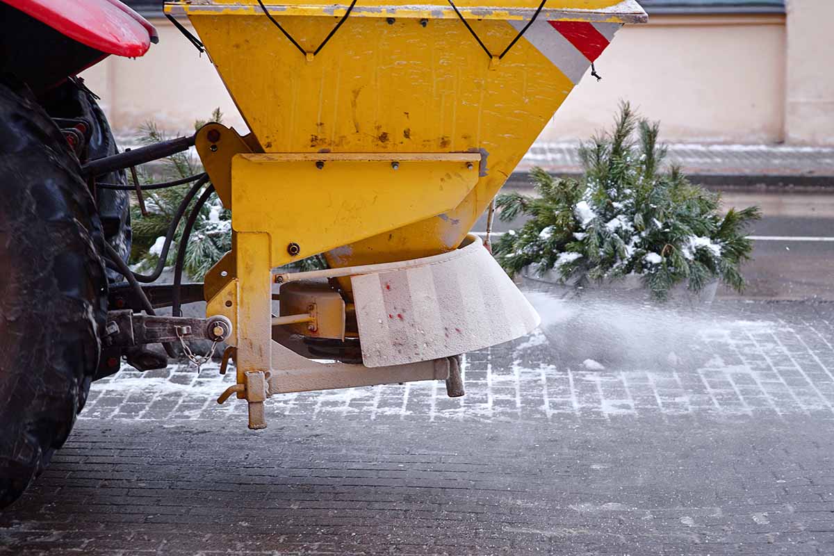A horizontal shot of a salt truck spreading salt onto asphalt surfaces in the winter.
