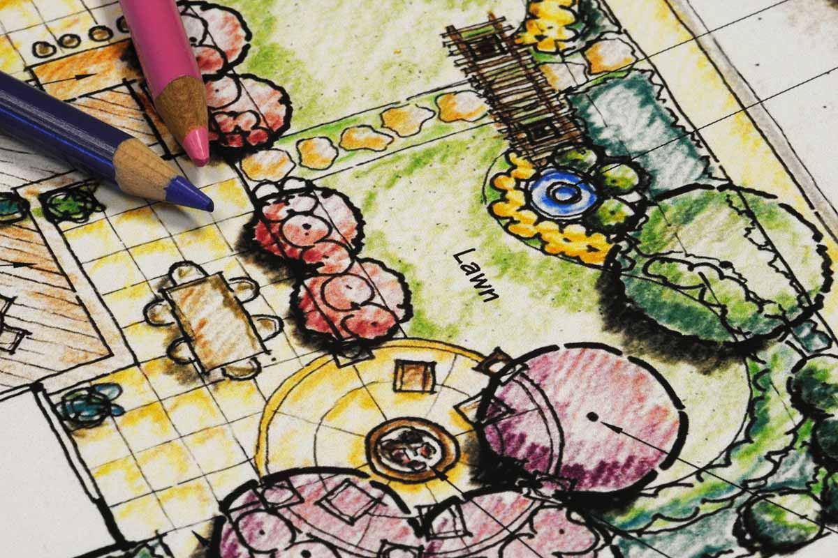A close up horizontal image of a garden design drawn on paper with two colored pencils to the top left of the frame.
