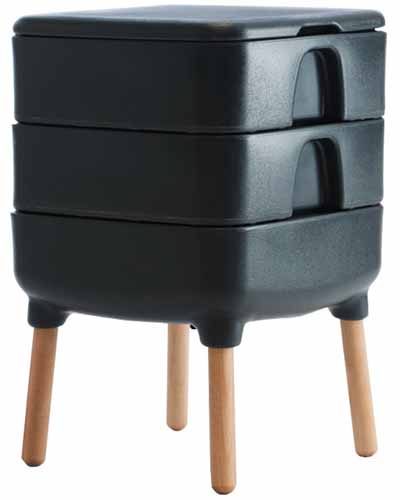 A close up of a black Hot Frog Living Composter on wooden legs isolated on a white background.