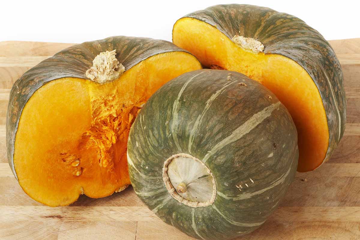 A close up horizontal image of buttercup squash cut in half set on a wooden surface.