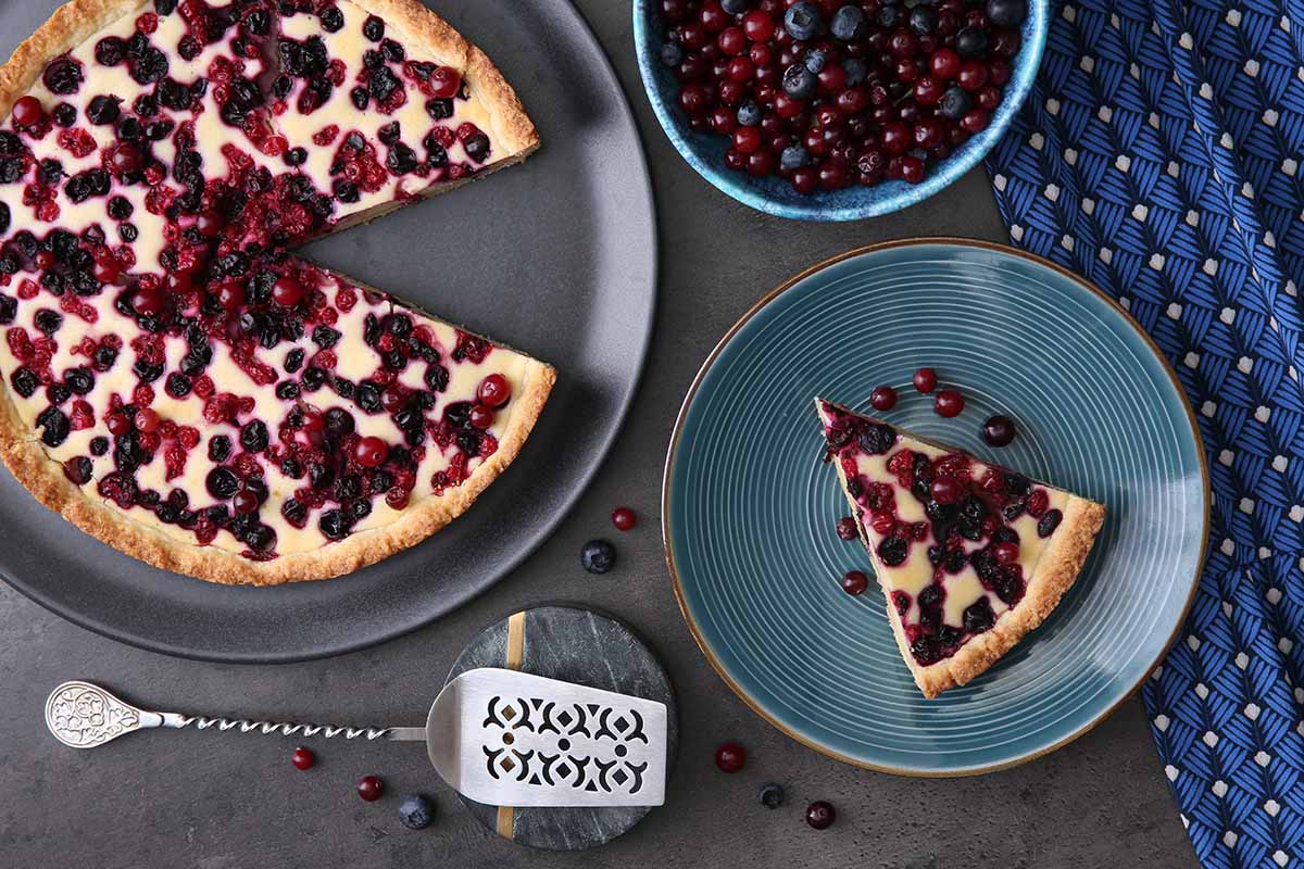 A close up top down image of a delicious looking currant pie with berries set on a gray table.